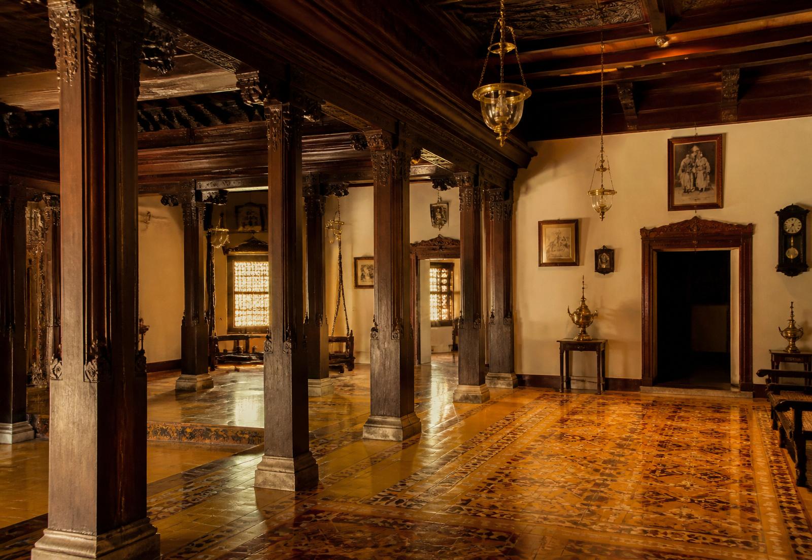 Interior of a traditional South Indian heritage home with carved pillars and patterned tiles